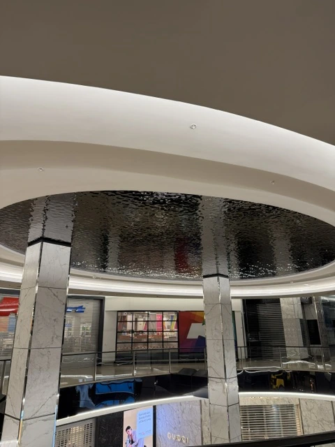 Close-up of reflective water ripple stainless steel ceiling panels above the Westfield Bondi retail interior
