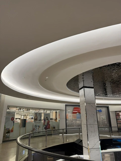 Curved white ceiling surrounding decorative water ripple stainless steel panels at Westfield Bondi