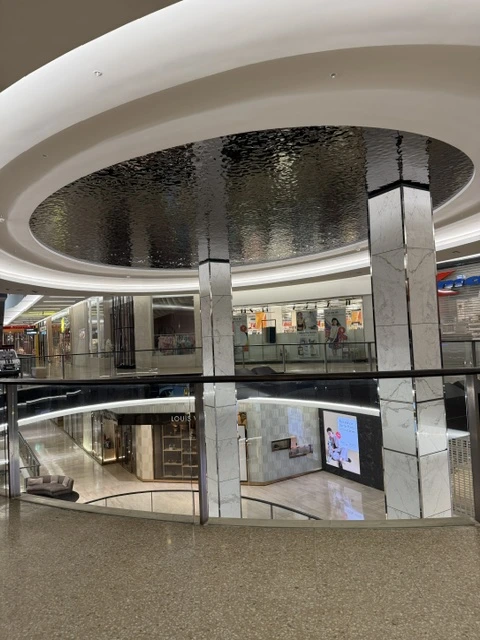Wide view of a circular water ripple stainless steel ceiling installation at Westfield Bondi, NSW